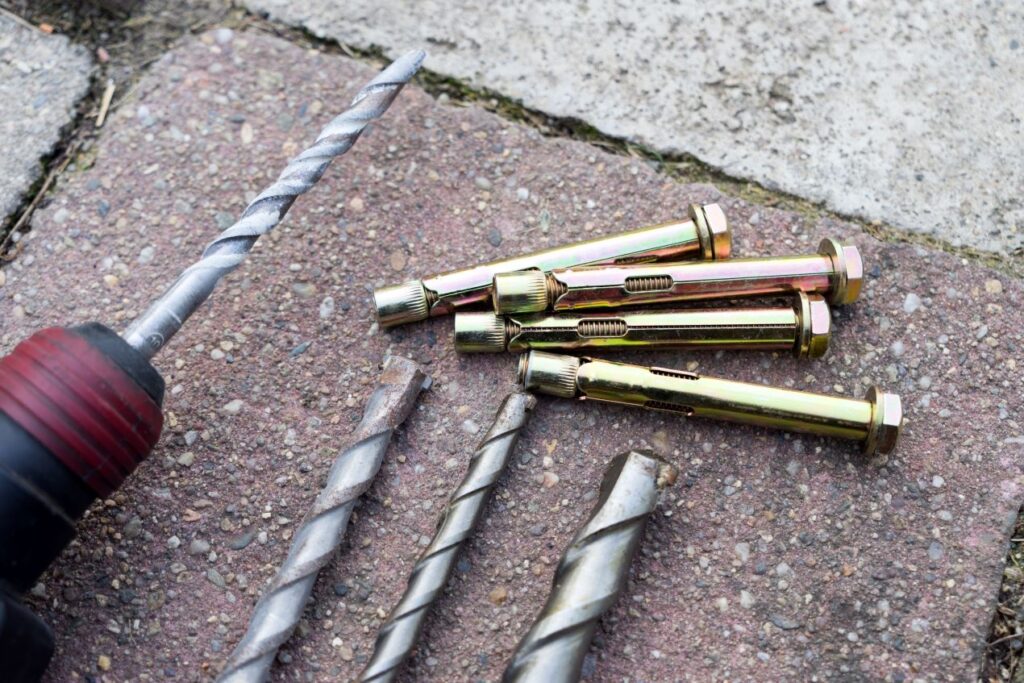 Bohrer und Schwerlastduebel liegen bereit fuer die sichere Montage schwerer Objekte an Beton oder Stein.